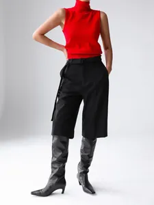 Minimalist red high-neck sleeveless knit vest paired with black culottes and boots.