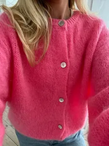 Nahaufnahme eines flauschigen pinkfarbenen Strickcardigans mit eleganten Perlmuttknöpfen