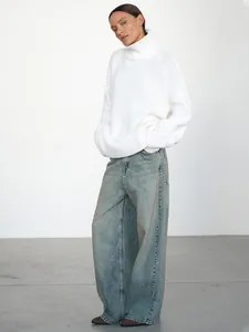 Elegante maglione a collo alto bianco oversize abbinato a jeans larghi in studio