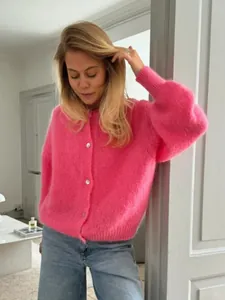 Nahaufnahme eines leuchtend rosa flauschigen Cardigans mit Perlenknöpfen