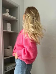 Seitenansicht einer leuchtend rosa mohair-strickjacke an einem model im lifestyle-stil