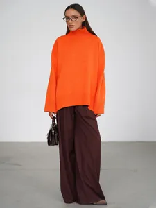 Donna che indossa un maglione arancione oversize lavorato a maglia a collo alto in studio
