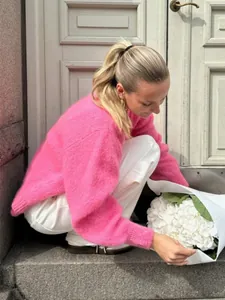 Leuchtend rosa Strickjacke mit seitlichem Schlitz im Lifestyle-Szenario präsentiert