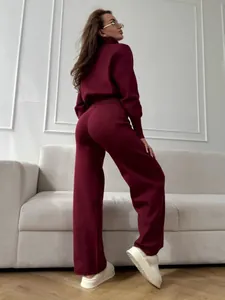 Back view of a woman wearing a chic burgundy zippered knit sweater and wide-leg pants set