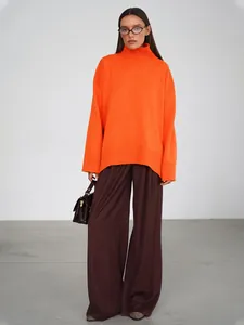 Modella che indossa un maglione a collo alto arancione e pantaloni larghi marroni