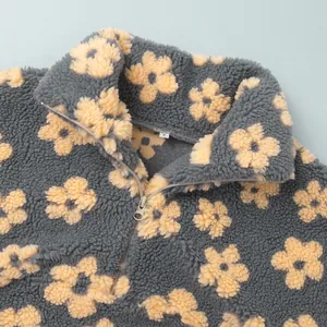 Close-up detail of gray fleece sweatshirt with yellow floral pattern and half-zip collar
