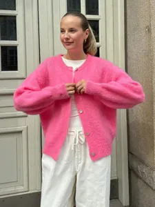 Streetstyle-Ansicht einer Frau in einem leuchtend rosa Strick-Cardigan mit Knöpfen.