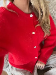 Nahaufnahme eines leuchtend roten Strick-Cardigans mit eleganten einreihigen Perlmuttknöpfen.