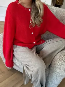 Detailansicht eines lebhaften roten Strick-Cardigans mit einreihigen weißen Knöpfen.