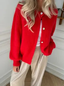 Detailansicht eines weichen roten Strick-Cardigans mit weißen Knöpfen und flauschiger Textur.