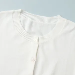 Detailed macro view of white knitted cardigan round neck featuring ribbed trim and buttons