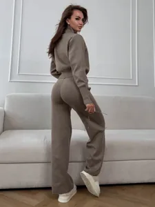 Side view of woman in taupe knitted set with double zipper sweater and wide pants