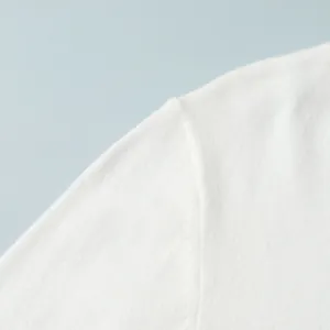 Close-up detail showing the soft texture and shoulder seam of a white knitted sweater