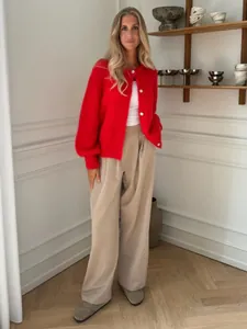 Fotomodel trägt eine rote einreihige Strickjacke mit weißen Knöpfen in hellem Raum