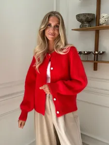 Süße rote Strickjacke mit weißen Knöpfen, getragen von einem Model in gemütlichem Ambiente