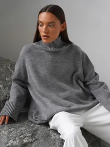 Primo piano di un maglione da donna grigio oversize a collo alto con trama a coste.