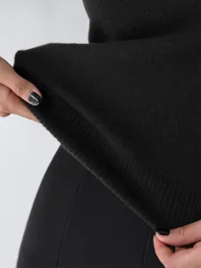 Detailed close-up of a black knitted vest hem showing ribbed finish and soft fabric texture