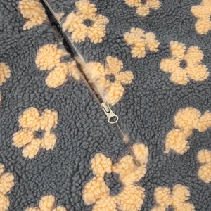 Macro view of soft grey fleece hoodie showing yellow floral pattern and metal zipper closure