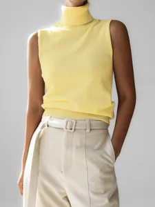 Detail of a minimalist yellow knitted sleeveless turtleneck vest for autumn styling.