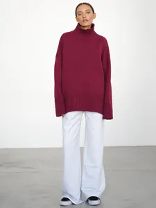 Vista a figura intera di una donna con un maglione bordeaux a collo alto e pantaloni grigi