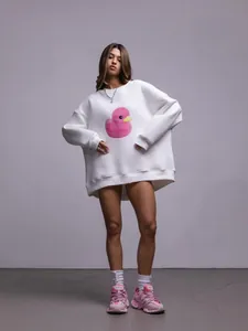 Modella indossa una felpa bianca oversize con una stampa grafica a forma di papera rosa