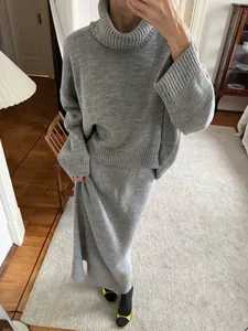 Detailed view of grey loose turtleneck sweater and matching long knit skirt set for winter