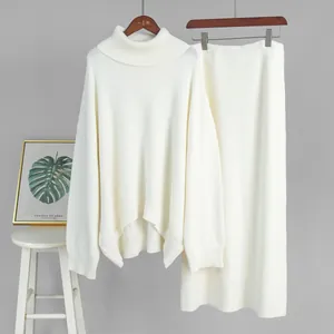 Cream-white knit set displayed on hangers against a grey wall with minimalist home decor