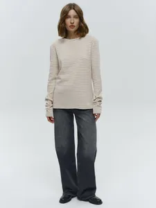Beige gestreept T-shirt met lange mouwen en een donkergrijze jeans met wijde pijpen.