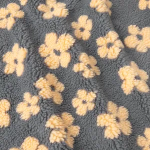 Close-up of soft gray and yellow floral pattern fleece fabric for warm winter hoodies.