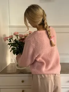 Detaillierte Rückansicht rosa Mohair-Strickjacke mit blondem Zopf und rosa Rosen