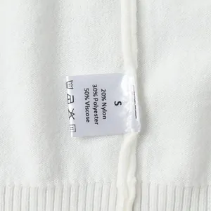 Close-up of white knit sweater care label showing material composition and size