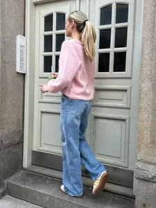 Modell zeigt einen süßen rosa Strickpullover kombiniert mit hellblauen weiten Jeans