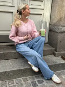 Süßer rosa Strick-Cardigan mit einreihigem Design und Jeans in einem Streetstyle-Look