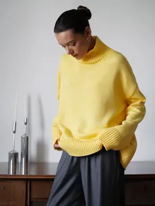 Dettaglio di un maglione a collo alto giallo oversize da donna in un ambiente interno minimalista