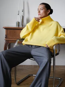 Elegante maglione a collo alto giallo oversize indossato da una modella in camera