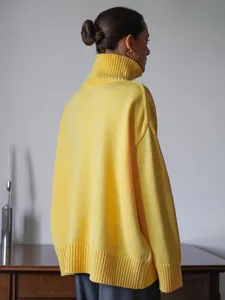 Dettaglio di un maglione a collo alto giallo brillante oversize in maglia spessa.