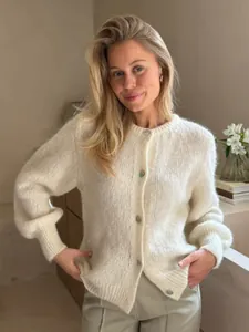 Detailansicht einer eleganten cremefarbenen Strickjacke mit flauschiger Textur.