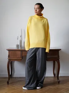 Modello con maglione a collo alto giallo oversize e pantaloni grigi a gamba larga
