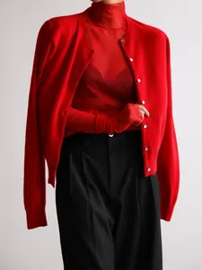 Close-up detail showing the texture of the red knit cardigan and sheer red turtleneck set