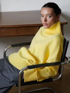 Modella che indossa un comodo maglione a collo alto giallo in un ambiente di classe.