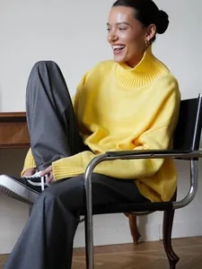Modella con maglione a collo alto giallo brillante oversize in un ambiente moderno