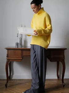 Modello che indossa un maglione a dolcevita giallo acceso a maglia larga con polsini