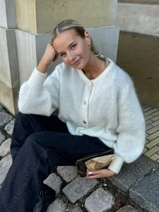 Detailansicht eines weichen weißen Strick-Cardigans, getragen von einem Modell im Freien