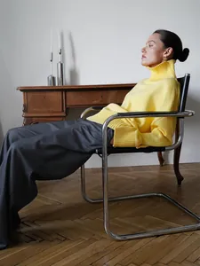 Primo piano di un maglione giallo a collo alto oversize in un ambiente elegante