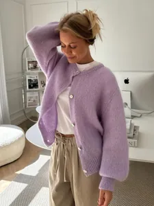 Detailansicht eines weichen lavendelfarbenen Strick-Cardigans mit weißen Knöpfen auf weißem T-Shirt.