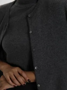 Close-up of grey knitwear set showing turtleneck top and buttoned cardigan texture