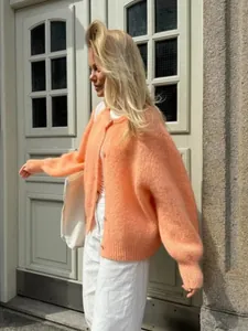 Detailansicht eines bonbonfarbenen Strick-Cardigans an einem Model in Außenaufnahme.