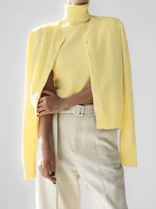 Close-up of yellow knitwear set with sleeveless high-neck top and button-up cardigan