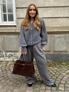 Detailansicht eines grauen Strick-Cardigans mit weiter Hose und brauner Tragetasche