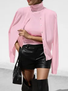 Detail of elegant pink knitwear set with sleeveless turtleneck and matching buttoned cardigan.